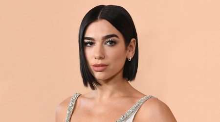 Dua Lipa poses with neck length hair with one ear showing.